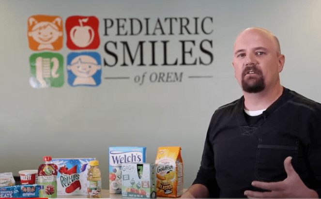 Dr. next to a table with fruit snacks and talking about it