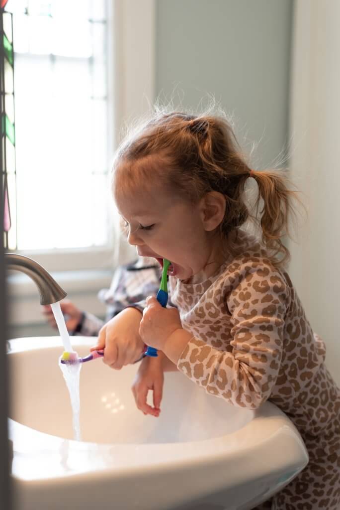 Young girl developing good oral hygiene habits at home by brushing her teeth.
